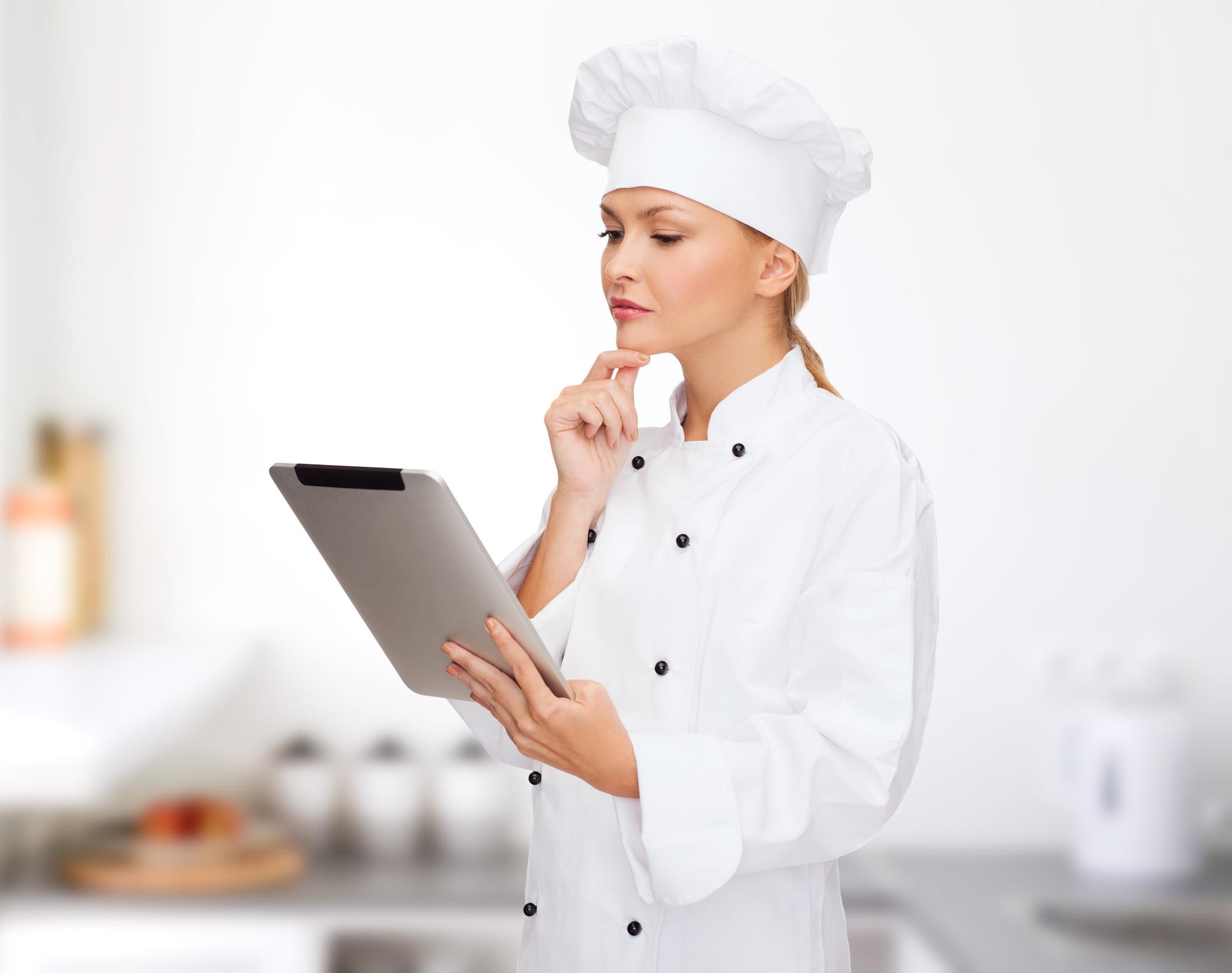 Chef writing a menu on tablet in small kitchen